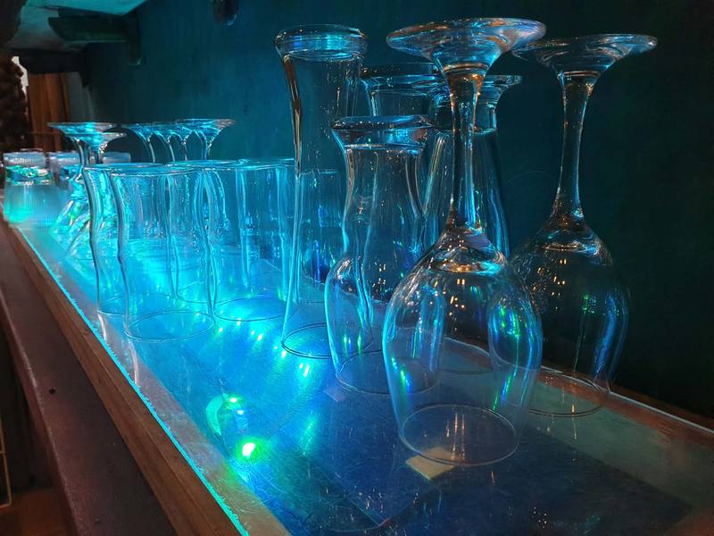 Rows of wine glasses lit blue along the bar.