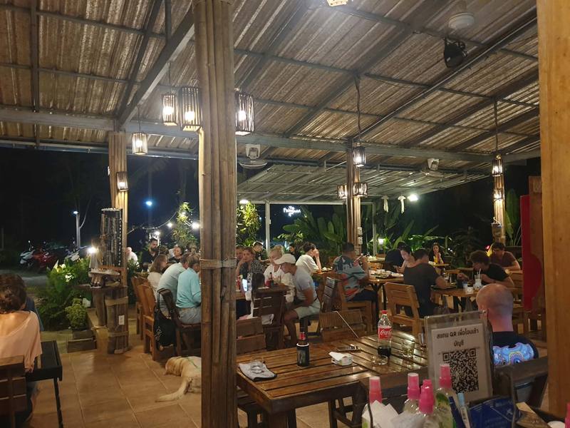 The open timber dining hall of The Fisherman Hut at night, lit by hanging lamps.