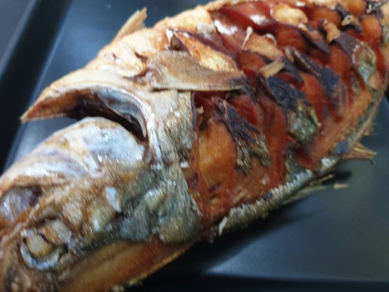 Close-up of a grilled fish with crisp, blistered skin.